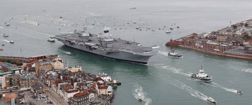 A photo of an aircraft carrier coming into dock